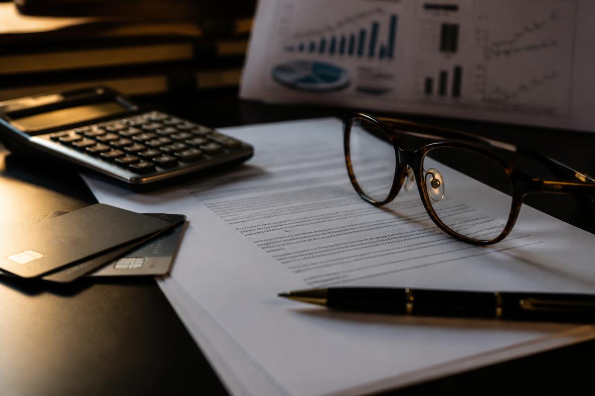 Contrato bancário, cartões e calculadora sobre mesa escura